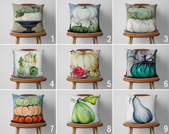 Könnte beinhalten: Neun verschiedene Designs für Dekokissen mit verschiedenen Herbstmotiven von Kürbissen, Kürbissen und Blättern. Die Kissen sind alle weiß mit verschiedenen Farben und Mustern.