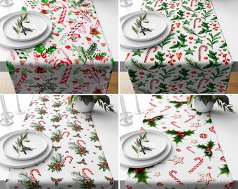 Op de afbeelding: Vier witte tafelrunners met een kerstthema. Elke runner heeft een ander patroon van rode en groene pepermuntstokken, hulstbladeren en bessen. De runners zijn perfect om een feestelijke touch aan elke kersttafel te geven.