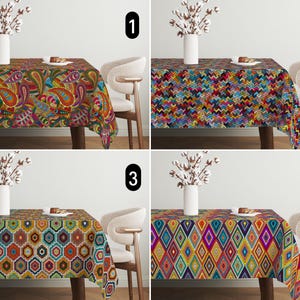 Op de afbeelding: Vier kleurrijke tafelkleden met verschillende patronen worden getoond. De patronen omvatten paisley, zigzags, geometrische zeshoeken en ruitvormen. Elk rechthoekig tafelkleed ligt op een houten tafel, met een vaas met witte bloemen en een stoel op de achtergrond.