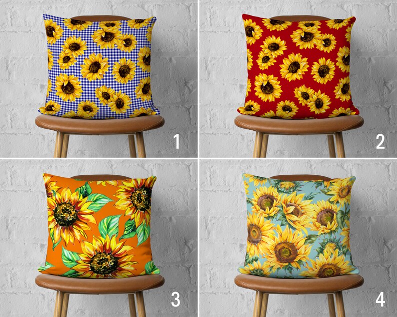 May include: Four different pillow designs featuring sunflowers. The pillows are displayed on brown chairs with a white brick background. The first pillow has a blue and white gingham pattern with sunflowers. The second pillow has a red background with sunflowers. The third pillow has an orange background with sunflowers. The fourth pillow has a light blue background with sunflowers.