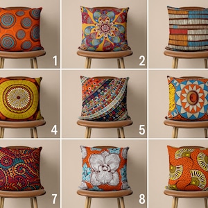 Op de afbeelding: Negen verschillende kussenhoezen met verschillende kleurrijke geometrische en bloemmotieven. De kussens worden gepresenteerd op stoelen met bruine houten frames.