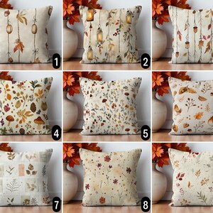 Könnte beinhalten: Neun dekorative Zierkissen mit herbstlichen Designs. Kissen mit verschiedenen Mustern, darunter Blätter, Eicheln, Laternen und Blumenarrangements in Braun-, Orange- und Cremetönen. Die Kissen werden vor Vasen mit Herbstlaub ausgestellt.