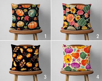 Könnte beinhalten: Vier Kissenbezüge mit verschiedenen Herbstmotiven. Jeder Kissenbezug hat einen schwarzen Hintergrund mit verschiedenen bunten Kürbissen, Blättern und Blumen.