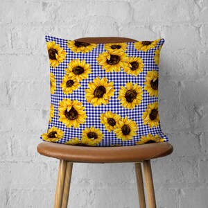 May include: A blue and white gingham pillow with a sunflower pattern. The pillow is made of fabric and has a square shape.