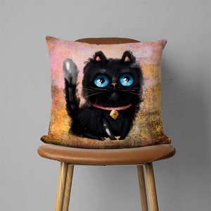 May include: A black cat with blue eyes and a pink collar with a gold bell sits on a pink and orange patterned pillow.