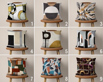 Könnte beinhalten: Neun verschiedene Designs für Dekokissen mit abstrakten geometrischen Mustern in verschiedenen Farben, darunter Schwarz, Weiß, Grau, Braun, Gelb, Rot, Blau und Grün. Die Kissen werden auf Stühlen mit braunen Holzbeinen gezeigt.