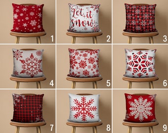 May include: Nine different red and white throw pillow designs featuring snowflakes and plaid patterns. Some pillows have the text "Let it snow" printed on them.
