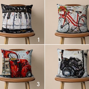May include: Four decorative throw pillows with different designs. The pillows are on brown chairs with wooden legs. The pillows feature a piano keyboard, a bicycle, a red truck, and a camera.