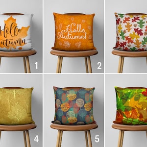 May include: Six different throw pillow designs with autumn themes. The pillows are on chairs with brown wooden legs. The pillows feature various patterns and colors, including orange, yellow, brown, and green. The pillows have text that says "Hello Autumn" and "Autumn".