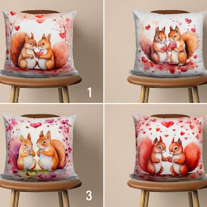 Peut inclure: Quatre coussins décoratifs avec un fond blanc et un motif aquarelle de deux écureuils tenant des cœurs. Les écureuils sont rouge-orange et les cœurs sont rouges. L'arrière-plan est décoré de cœurs rouges et de fleurs roses.