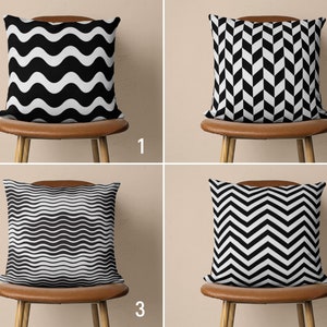 May include: Four throw pillows with black and white geometric patterns. The pillows are arranged on four chairs with brown leather seats. The chairs are against a beige wall.
