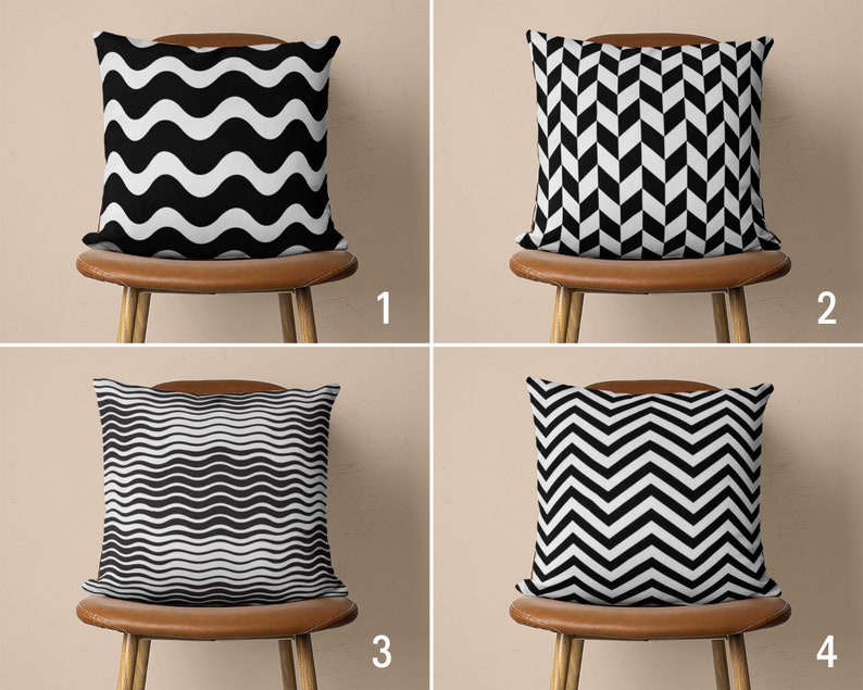 May include: Four throw pillows with black and white geometric patterns. The pillows are arranged on four chairs with brown leather seats. The chairs are against a beige wall.
