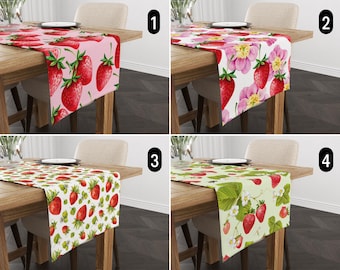May include: Four table runners with different strawberry designs. The runners are pink, white with pink flowers, white with green leaves, and green. The runners are all 14 inches wide and 70 inches long.