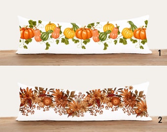 May include: Two white rectangular throw pillows with different designs. The first pillow has a border of green leaves and orange, yellow, and green pumpkins. The second pillow has a border of brown and orange flowers.