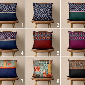 May include: Nine different throw pillow designs with various patterns and colors. The pillows are displayed on chairs with wooden frames.