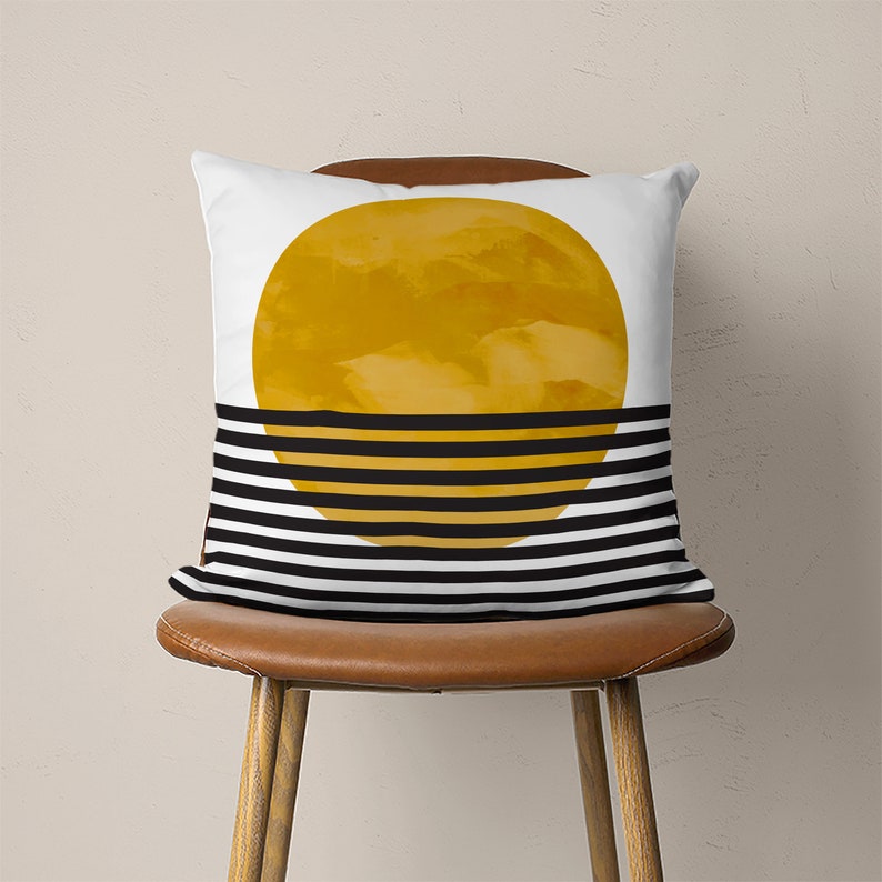 May include: A white throw pillow with a black and white striped pattern and a large yellow circle in the center.