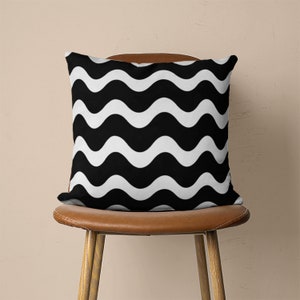 May include: Black and white wave patterned throw pillow on a brown leather chair.