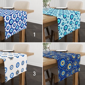 May include: Four table runners with different patterns of blue evil eyes on a white, blue, or gold background. The table runners are on wooden tables with a white background.