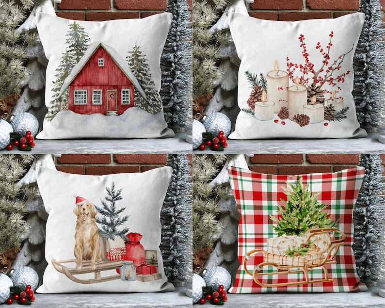 May include: Four different Christmas pillow designs. The first pillow features a red cottage with snow on the roof and pine trees. The second pillow features a white background with candles, pine cones, and red berries. The third pillow features a golden retriever wearing a Santa hat and pulling a sled with a Christmas tree. The fourth pillow features a red and green plaid pattern with a Christmas tree in a sleigh.
