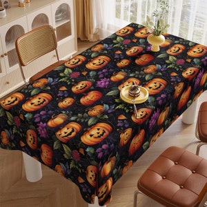 May include: Black tablecloth with a Halloween-themed pattern of orange jack-o'-lanterns with purple flowers and green leaves.