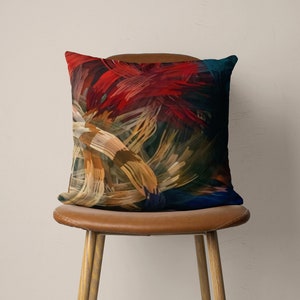 May include: A throw pillow with an abstract design featuring a mix of red, orange, yellow, blue, and green brushstrokes.