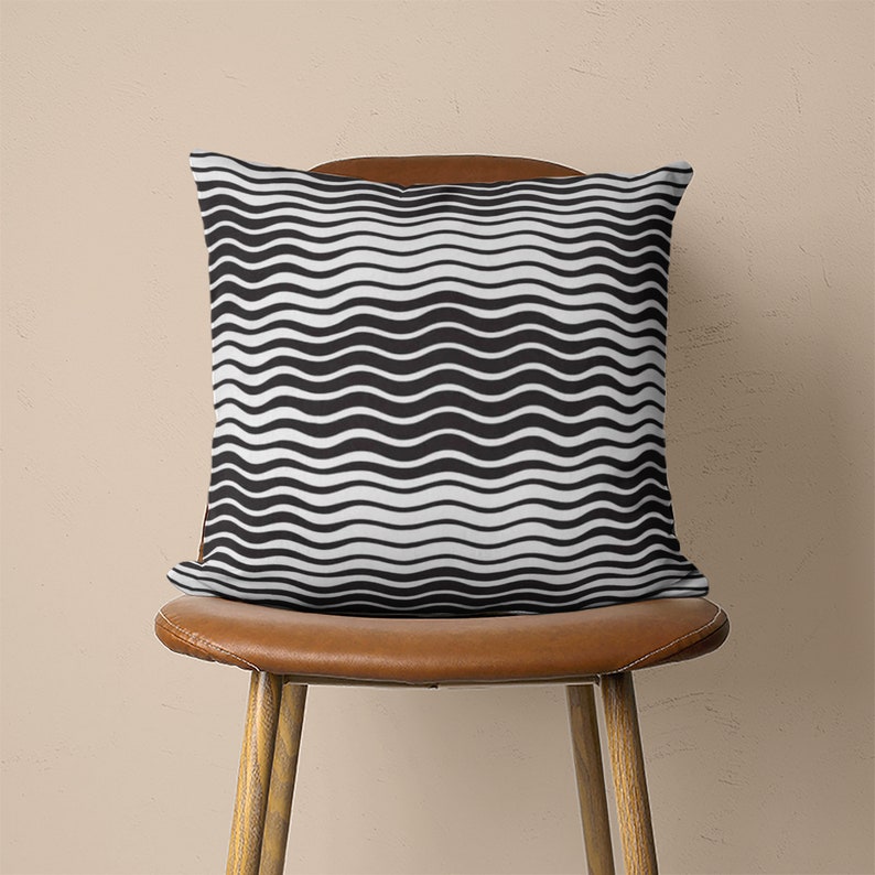 May include: A black and white wavy patterned throw pillow on a brown leather chair.