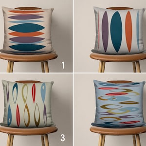 May include: Four different throw pillow designs with abstract geometric patterns in shades of blue, red, orange, yellow, and purple. The pillows are displayed on brown chairs with wooden legs.