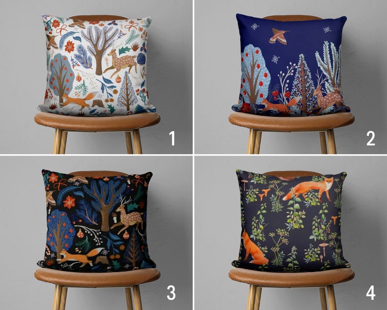 Puede incluir: Cuatro cojines decorativos con diferentes patrones de tem&aacute;tica forestal. Los cojines presentan zorros, ciervos y &aacute;rboles en tonos de azul, verde, rojo y blanco. Los cojines se muestran en sillas marrones sobre un fondo blanco.