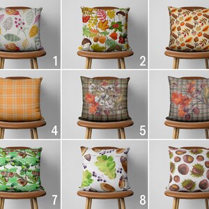 May include: Nine different throw pillow designs featuring autumnal themes. The pillows are displayed on chairs with brown wooden frames. The pillows feature various patterns and colours, including plaid, floral, and acorn designs.