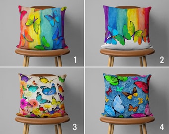 May include: Four decorative pillow covers with different butterfly designs. The first pillow cover features a rainbow background with colorful butterflies. The second pillow cover features a white background with a rainbow watercolor design and colorful butterflies. The third pillow cover features a floral background with colorful butterflies. The fourth pillow cover features a blue background with colorful butterflies.