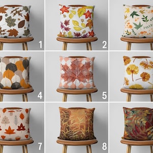 Puede incluir: Nueve dise&ntilde;os diferentes de cojines decorativos con motivos de hojas de oto&ntilde;o. Los cojines se muestran en sillas de madera con cojines marrones.