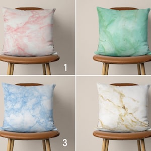 Pode incluir: Quatro cadeiras marrons com diferentes almofadas estampadas. As almofadas são de mármore rosa, verde, azul e branco com veios dourados.