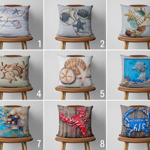 May include: Nine different pillow covers featuring a variety of beach-themed designs. The designs include seashells, starfish, fish, crabs, and nautical rope. The pillow covers are all displayed on brown wooden chairs.