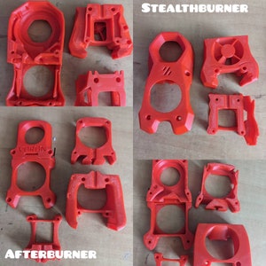 May include: A collection of 3D printed parts for a Voron 2.4 3D printer. The parts are red and have the words "Stealthburner" and "Afterburner" printed on them.