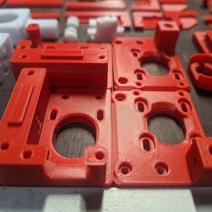 Puede incluir: Cuatro piezas de pl&aacute;stico rojo impresas en 3D con recortes circulares y bordes elevados. Las piezas est&aacute;n dispuestas en dos filas de dos.