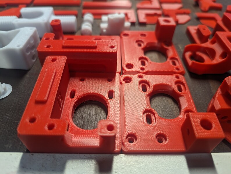 Puede incluir: Cuatro piezas de pl&aacute;stico rojo impresas en 3D con recortes circulares y bordes elevados. Las piezas est&aacute;n dispuestas en dos filas de dos.