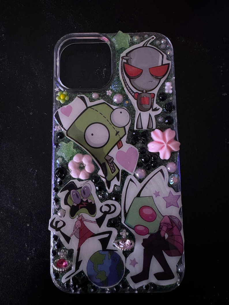 Puede incluir: Una funda transparente para tel&eacute;fono con un fondo brillante y personajes de dibujos animados de la serie animada Invader Zim. Los personajes incluyen a Zim, Gir y Dib. La funda est&aacute; decorada con corazones rosas, estrellas y flores.