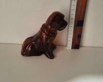 May include: A brown glass figurine of a dog sitting with its head turned to the side. The dog is about 6 inches tall.