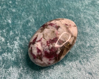 May include: A smooth, polished, oval-shaped stone with a white, pink, and brown marbled pattern.