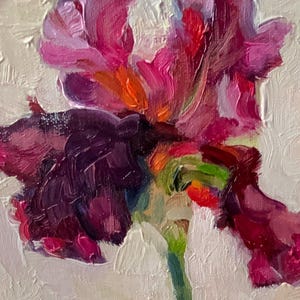 Close-up of a vibrant oil painting of an iris flower. The petals display shades of deep purple, magenta, and orange, with a green stem. The textured brushstrokes create a dynamic and artistic floral composition.