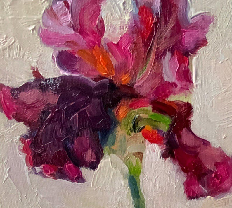 Close-up of a vibrant oil painting of an iris flower. The petals display shades of deep purple, magenta, and orange, with a green stem. The textured brushstrokes create a dynamic and artistic floral composition.