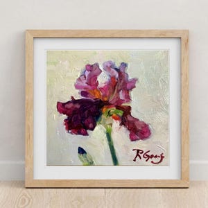May include: Framed oil painting of a vibrant iris flower. The artwork features a large, multi-petaled bloom in shades of deep purple and magenta, set against a textured, off-white background. The painting is signed in the lower right corner.