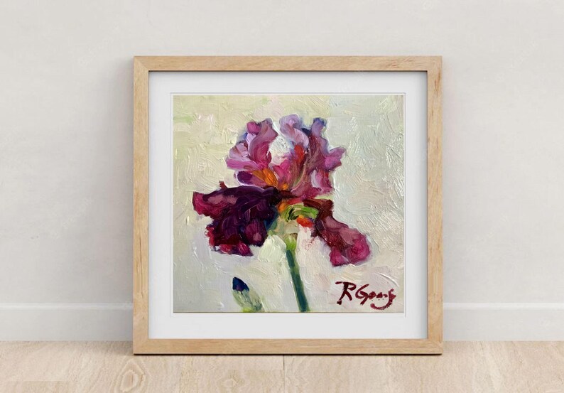 May include: Framed oil painting of a vibrant iris flower. The artwork features a large, multi-petaled bloom in shades of deep purple and magenta, set against a textured, off-white background. The painting is signed in the lower right corner.