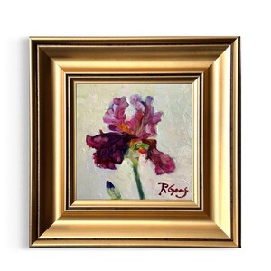 A framed oil painting of a purple iris flower. The flower has dark purple and magenta petals with a yellow center. The painting is in a gold frame and signed in the lower right corner.  Frame is not included.