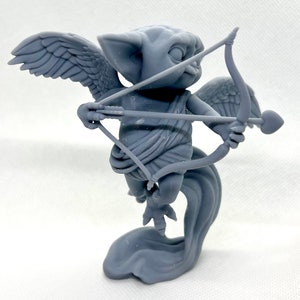 May include: A gray 3D printed figurine of a winged creature with a bow and arrow. The creature has large ears and a mischievous expression. The figurine is posed in a dynamic, flying position.
