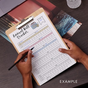 May include: A printable annual bill tracker on a clipboard with a hand holding a pen. The tracker has a calendar layout with columns for each month of the year and rows for different bills, such as rent, electricity, and internet. The tracker is labeled "Annual Bill Tracker" and "Year: 2024".