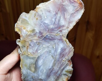 May include: A large, irregularly shaped piece of agate with a swirling pattern of white, purple, and brown. The agate has a smooth, polished surface.