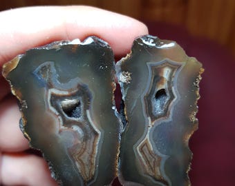 May include: Two halves of a geode with brown, gray, and white banding. The geode has a hollow center with a small opening.