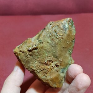 Peut inclure: Une roche brune rugueuse avec des d&eacute;p&ocirc;ts min&eacute;raux verts et orange. La roche est &agrave; peu pr&egrave;s de la taille de la main d'une personne.