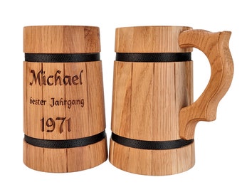 Op de afbeelding: Twee houten bierglazen met zwarte banden rond de boven- en onderkant. Het glas aan de linkerkant heeft de naam "Michael" gegraveerd, samen met de tekst "bester Jahrgang 1971".